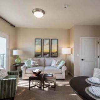 A cozy and well-decorated living room with soft neutral tones, featuring a sofa, artwork, and elegant lighting.