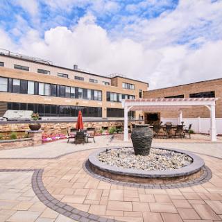 A serene courtyard featuring a central fountain, surrounded by modern architecture and comfortable seating areas.