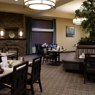 A cozy dining area with tables and booths, featuring warm lighting and tasteful decor.