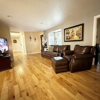 A cozy living room featuring leather sofas and a warm wooden floor.