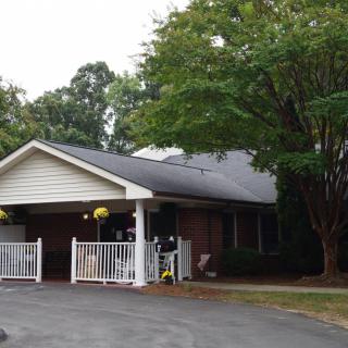 A single-story house with a driveway and trees in the front yard.