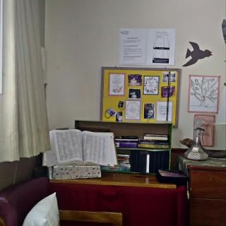 A cozy workspace featuring a cluttered desk with papers and decor on the walls.