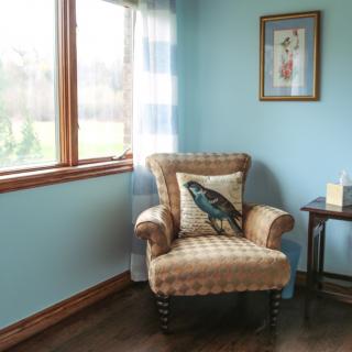 A cozy living room corner with an armchair, decorative pillow, and a side table.