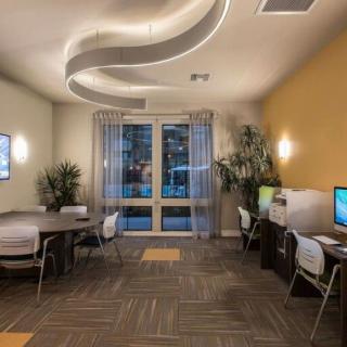A modern office workspace with computers, seating areas, and contemporary lighting.