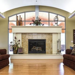 A cozy living room with a central fireplace flanked by two chairs and decorated with various ornaments.