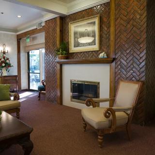 A cozy living room with a fireplace, wood paneling, and comfortable seating.