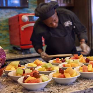 A chef prepares fruit bowls in the kitchen.