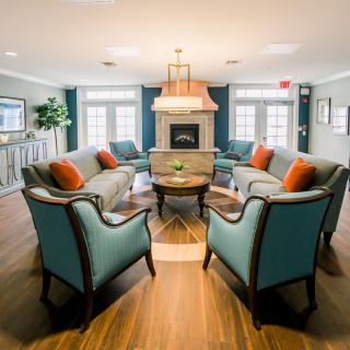 A cozy living room with a central fireplace, surrounded by elegant seating and accented with colorful cushions.