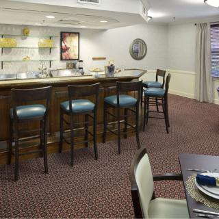 A cozy bar area with stools and a counter inside a furnished room.