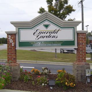 Entrance sign for Emerald Gardens with brick pillars and landscaping.