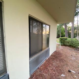 A side view of a building showcasing a window surrounded by greenery.