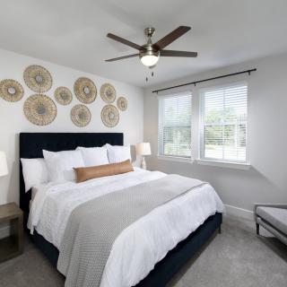 A modern bedroom with neutral tones, featuring a comfortable bed and decorative wall art.