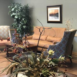 A cozy living room setup featuring a sofa, armchairs, and decorative plants.