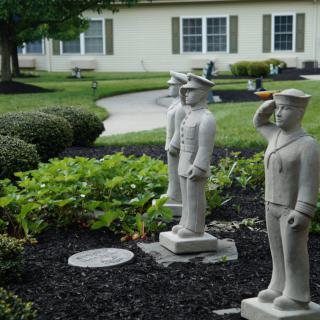 A garden features military-themed statues in front of a residential building.