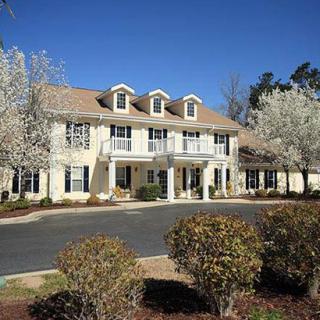 A large residential house with well-maintained landscaping and a driveway.