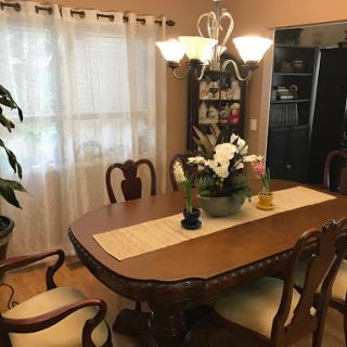 A cozy dining room featuring a wooden table, elegant chairs, and a floral centerpiece under a stylish light fixture.
