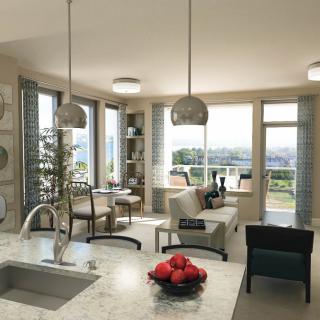 A modern open-plan kitchen and living room with large windows, allowing natural light to fill the space.