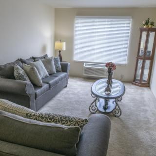 A cozy living room featuring a grey sofa set, coffee table, and soft lighting.
