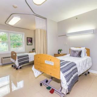 A clean and well-lit hospital room with two beds and a large window.