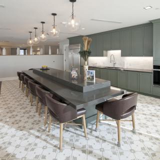 A modern kitchen with a large island and contemporary bar stools, featuring elegant lighting fixtures and a stylish marble floor.