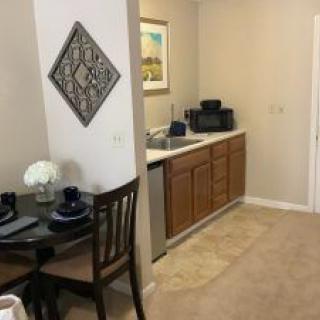 A cozy kitchenette and dining area in an apartment, featuring a small dining table set for two and compact kitchen appliances.