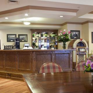 A welcoming hotel lobby featuring a wooden reception desk, floral arrangements, and cozy seating.