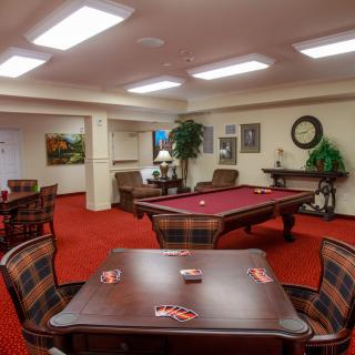 A cozy game room with a pool table and seating area on red carpet flooring.
