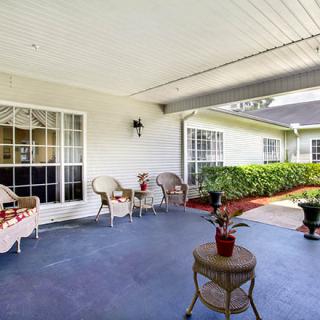 A cozy patio area with wicker furniture and potted plants under a covered space.
