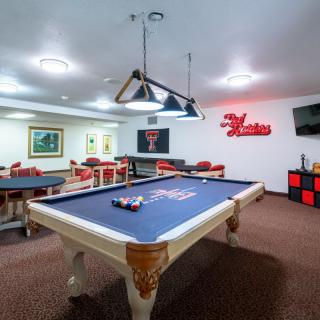 A well-lit game room featuring a pool table and recreational seating.