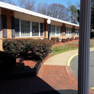 A one-story brick building with a landscaped walkway and bushes.