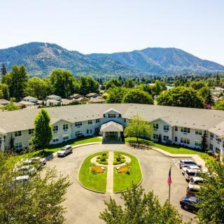 Aerial view of a circular driveway in front of a large building with mountains in the background.