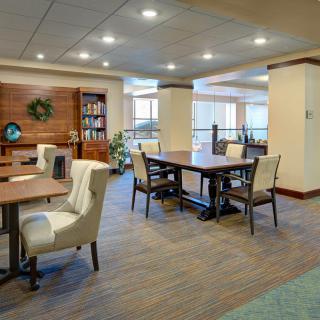 A modern lounge area with tables and chairs, featuring warm lighting and stylish decor.
