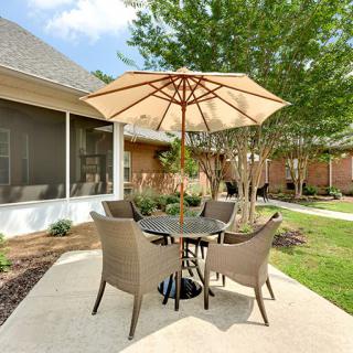 A cozy outdoor patio set with an umbrella, surrounded by a garden.