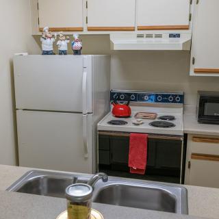 A compact kitchen with essential appliances including a refrigerator, stove, microwave, and sink.