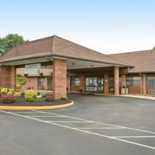 Exterior view of a hotel with a parking area and main entrance.