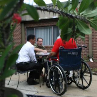 A group of people having a conversation outdoors, including one person in a wheelchair.