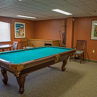 A cozy game room featuring a classic pool table with decor on the walls.