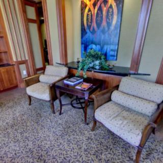 A cozy waiting area with two chairs, a small table, and decorative artwork.