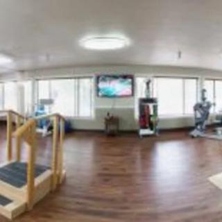 A spacious gym with exercise equipment and a TV on the wall.