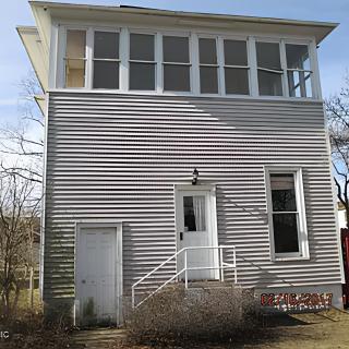 A two-story house with large windows and a small entrance porch.