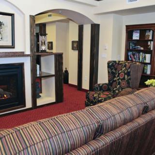 A cozy living room with a fireplace, striped sofa, and a well-stocked bookshelf.