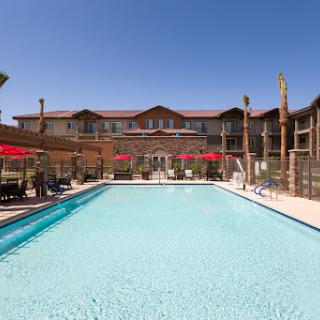A sunny day at a hotel pool surrounded by lounge chairs and umbrellas.