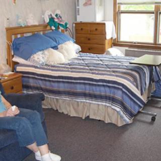 A cozy bedroom with a neatly made bed and a dresser by the window.