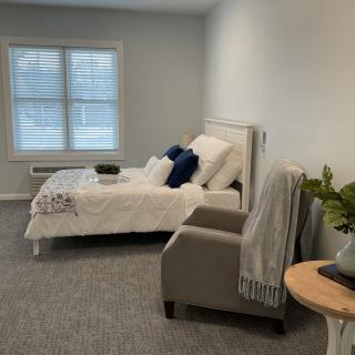 A minimalist bedroom with a cozy bed and a comfortable chair.