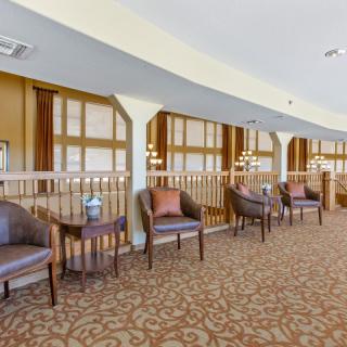 A cozy lobby seating area with chairs and tables arranged along a carpeted space.