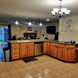 A modern kitchen with wooden cabinets, tile flooring, and a chandelier.