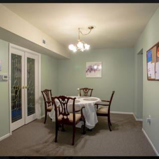 A cozy dining room with a table and chairs, adorned by a chandelier and artwork on the walls.