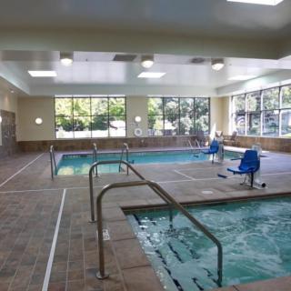 A spacious indoor swimming pool area featuring a hot tub and accessible lifts.