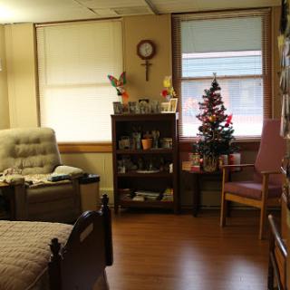 A cozy room featuring a bed, comfortable seating, and festive decorations including a small Christmas tree.
