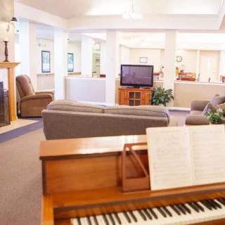 A cozy living room featuring a piano, fireplace, and comfortable seating area.